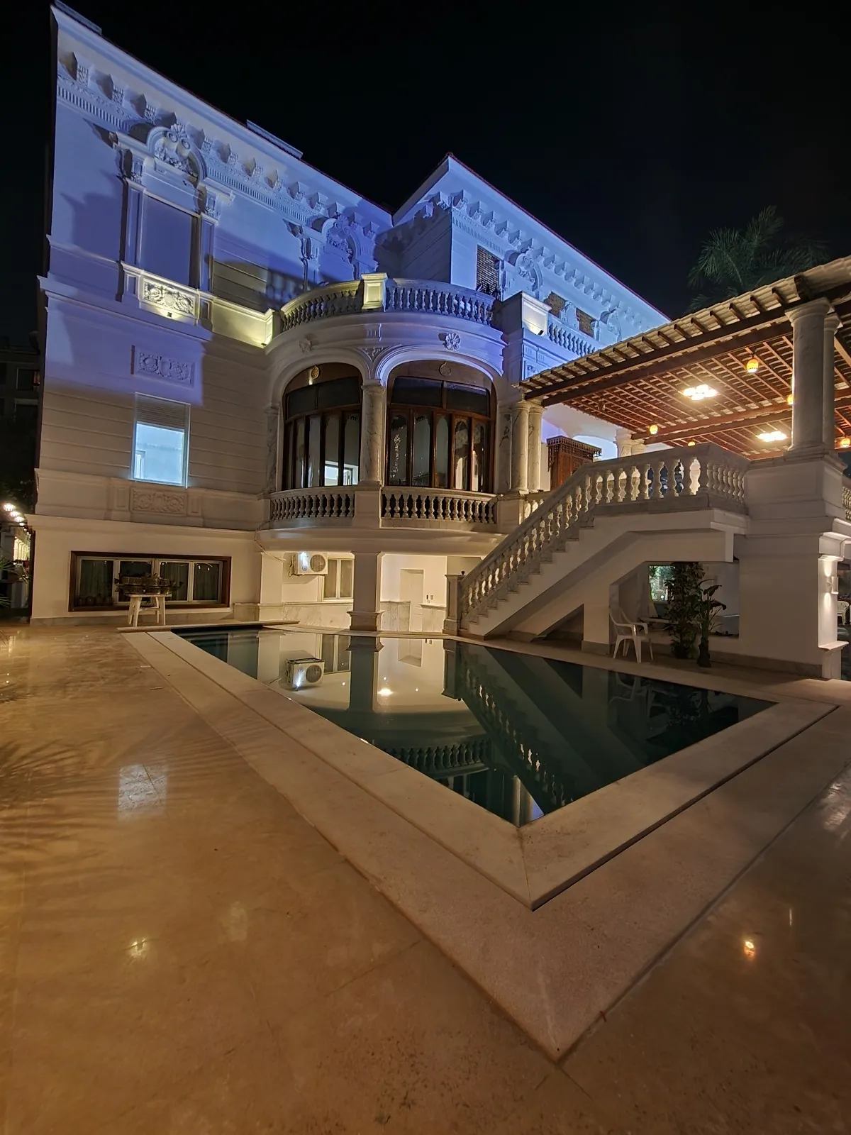 A vertical courtyard view with the pool, exterior stairs and illuminated facade